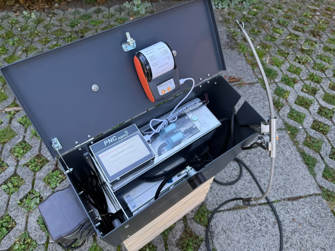 Geöffnetes PNC-nano mit Abgassonde und Protokolldrucker vor Ort